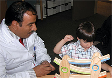 A doctor sitting next to a child playing