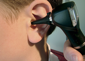 hand examining ear with otoscope