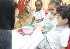 an educator showing children how to use a tooth brush